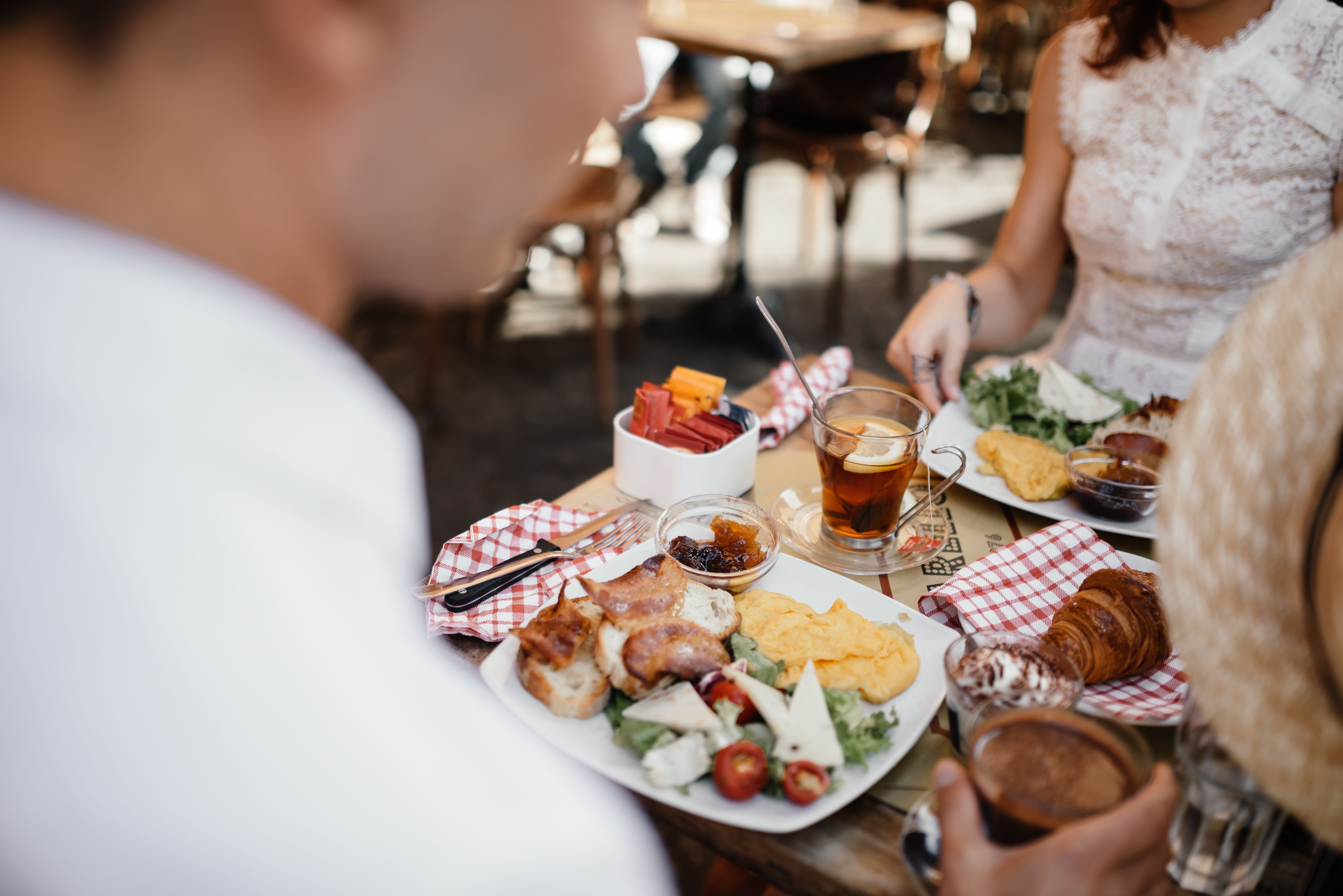 Friends sharing a relaxed meal at an outdoor cafe, representing safer and more comfortable inclusive dining.